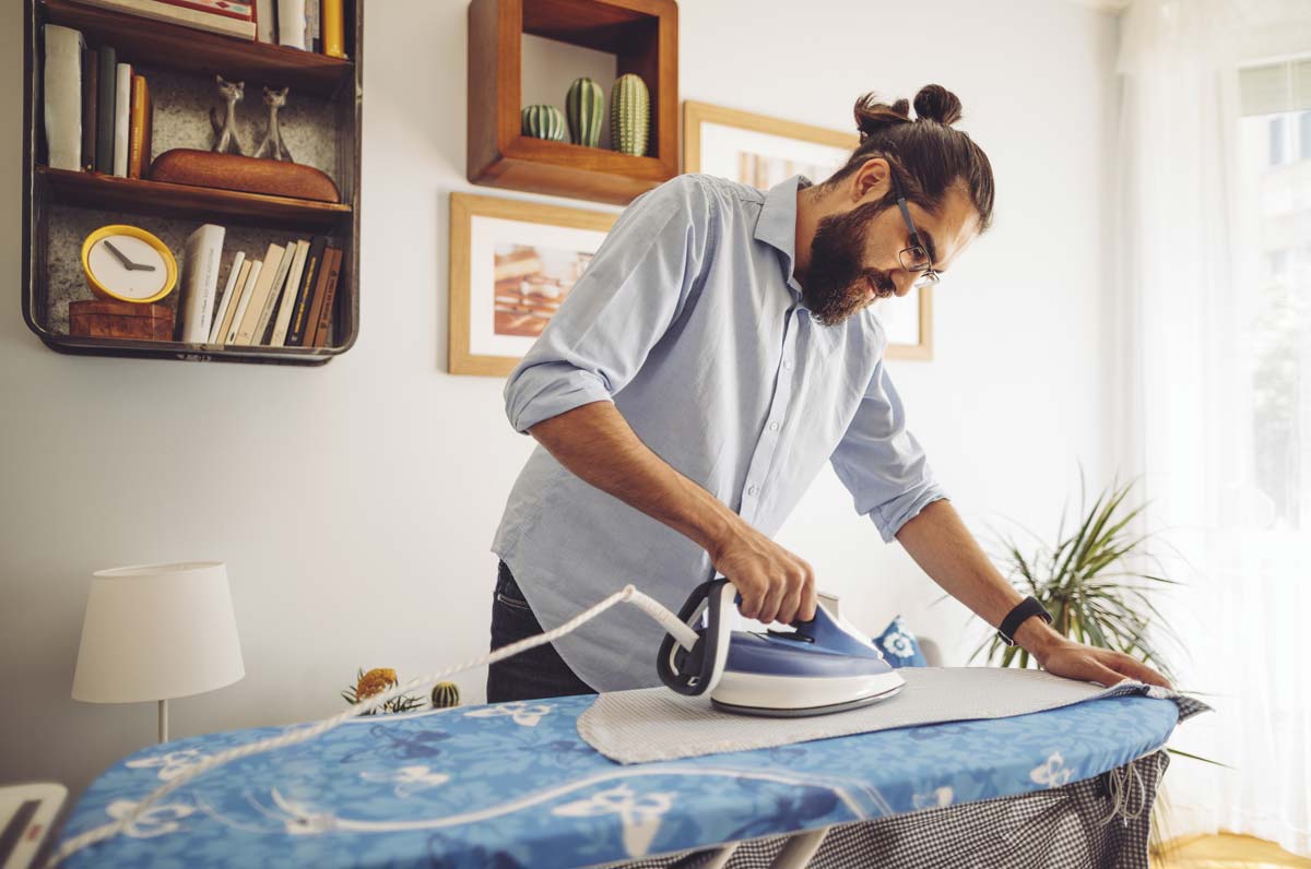 homem a passar a ferro em casa